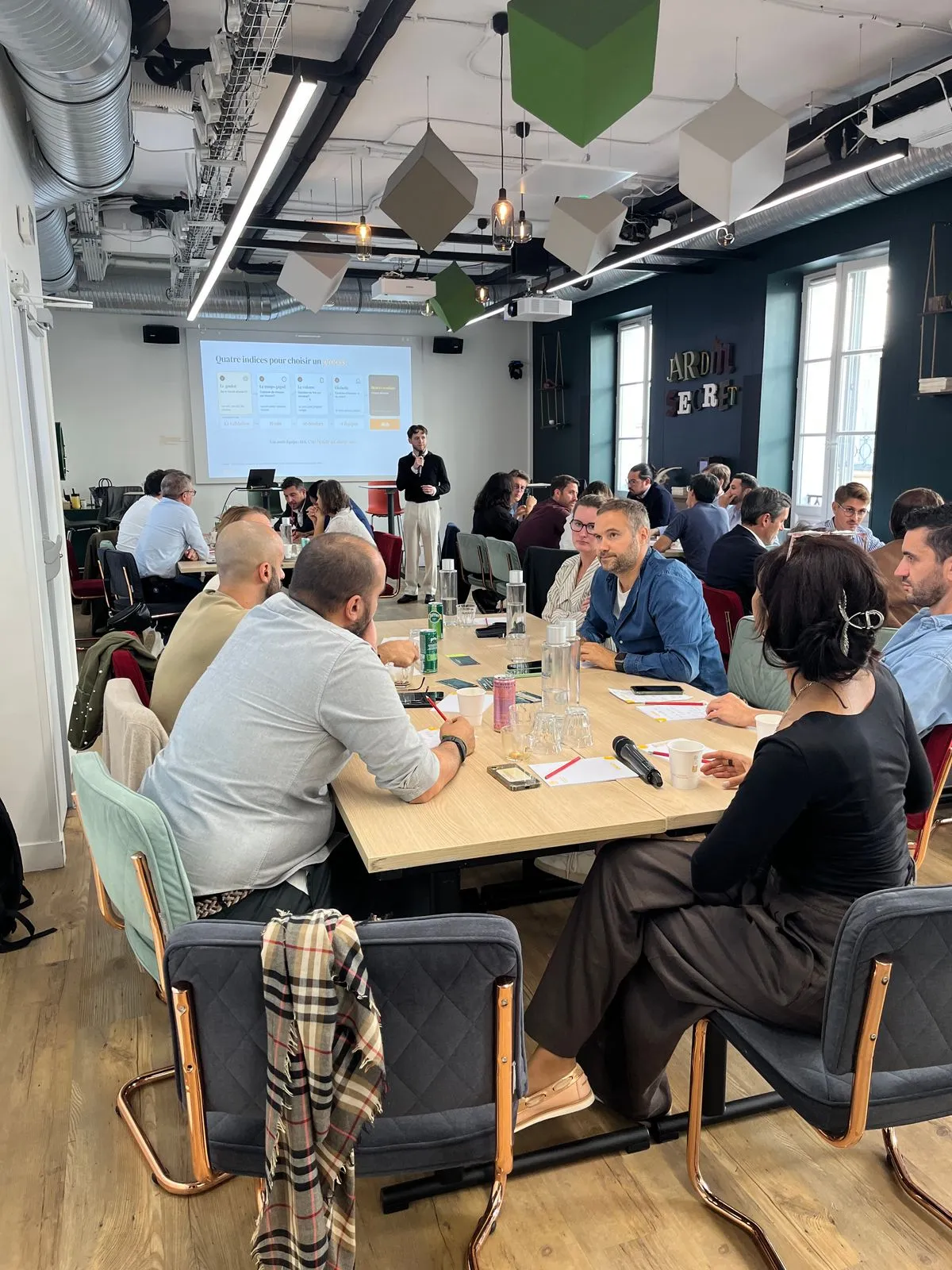 Une grande salle de participants en atelier, ordinateurs ouverts, face à une présentation