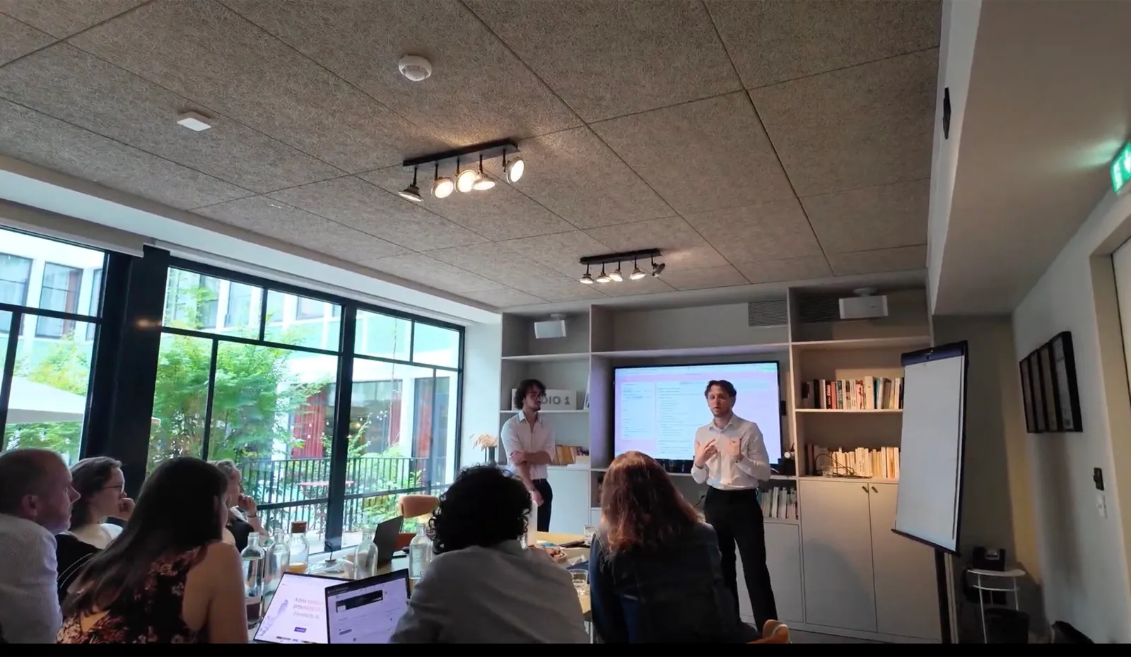 Clément Geynet et Enzo Donati animent un atelier IA devant une équipe en salle de réunion